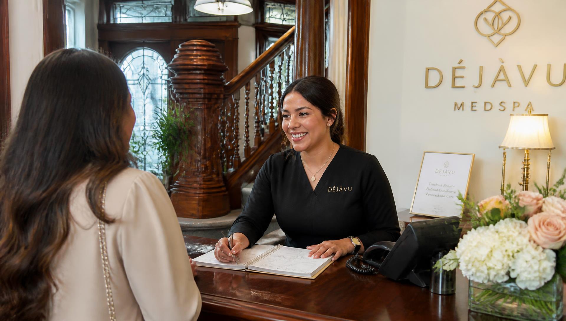 Receptionist welcoming a guest at the Bella Aesthetica front desk